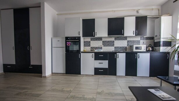 A modern kitchen with black and white cabinets, a microwave, and a kettle on the countertop. - Impeccable 1-bed Studio in Roșu (Chiajna)