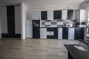 A modern kitchen with black and white cabinets, a microwave, and a kettle on the countertop.