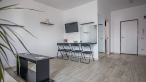 A modern room with a black table, four chairs, a flat-screen TV, and a small shelf with a teddy bear. - Impeccable 1-bed Studio in Roșu (Chiajna)