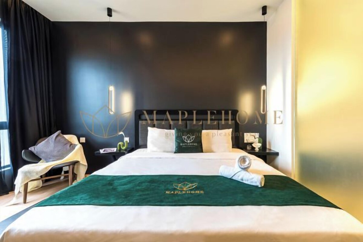 Une chambre d’hôtel avec un grand lit, une chaise, une table de chevet et un mur orné d’un logo.