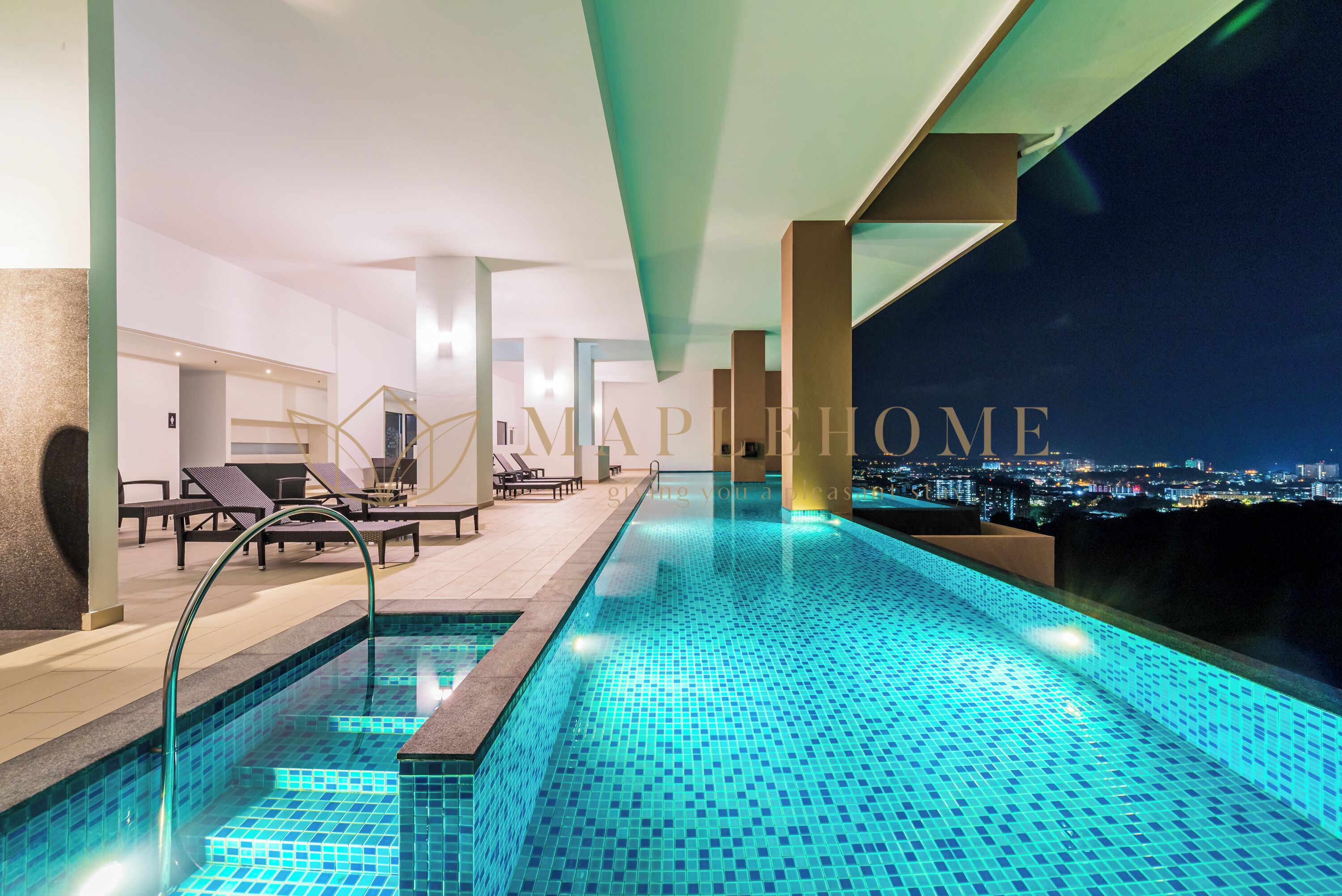 A modern indoor swimming pool with a city view at night.