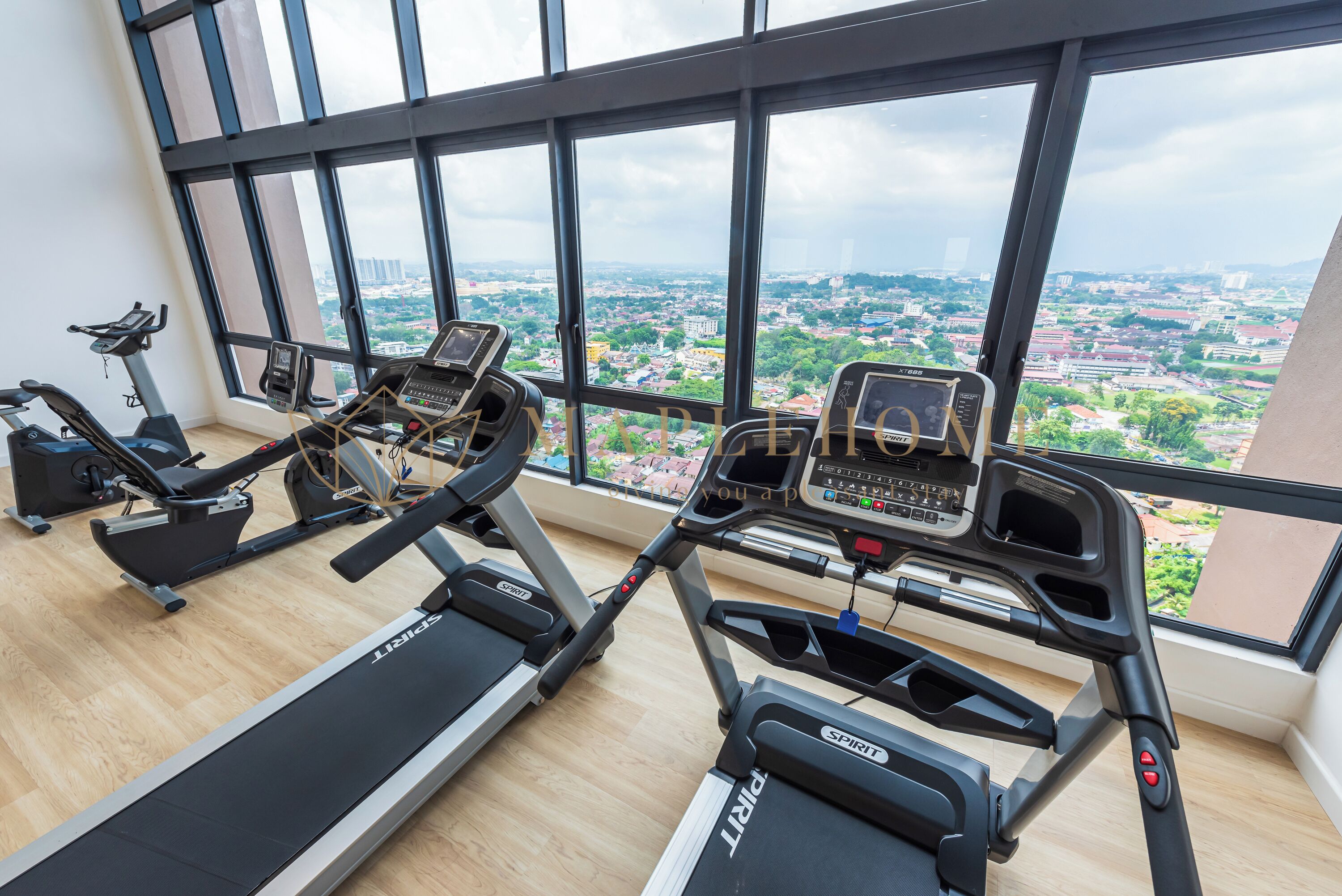 A gym with treadmills and exercise bikes, large windows with a city view.