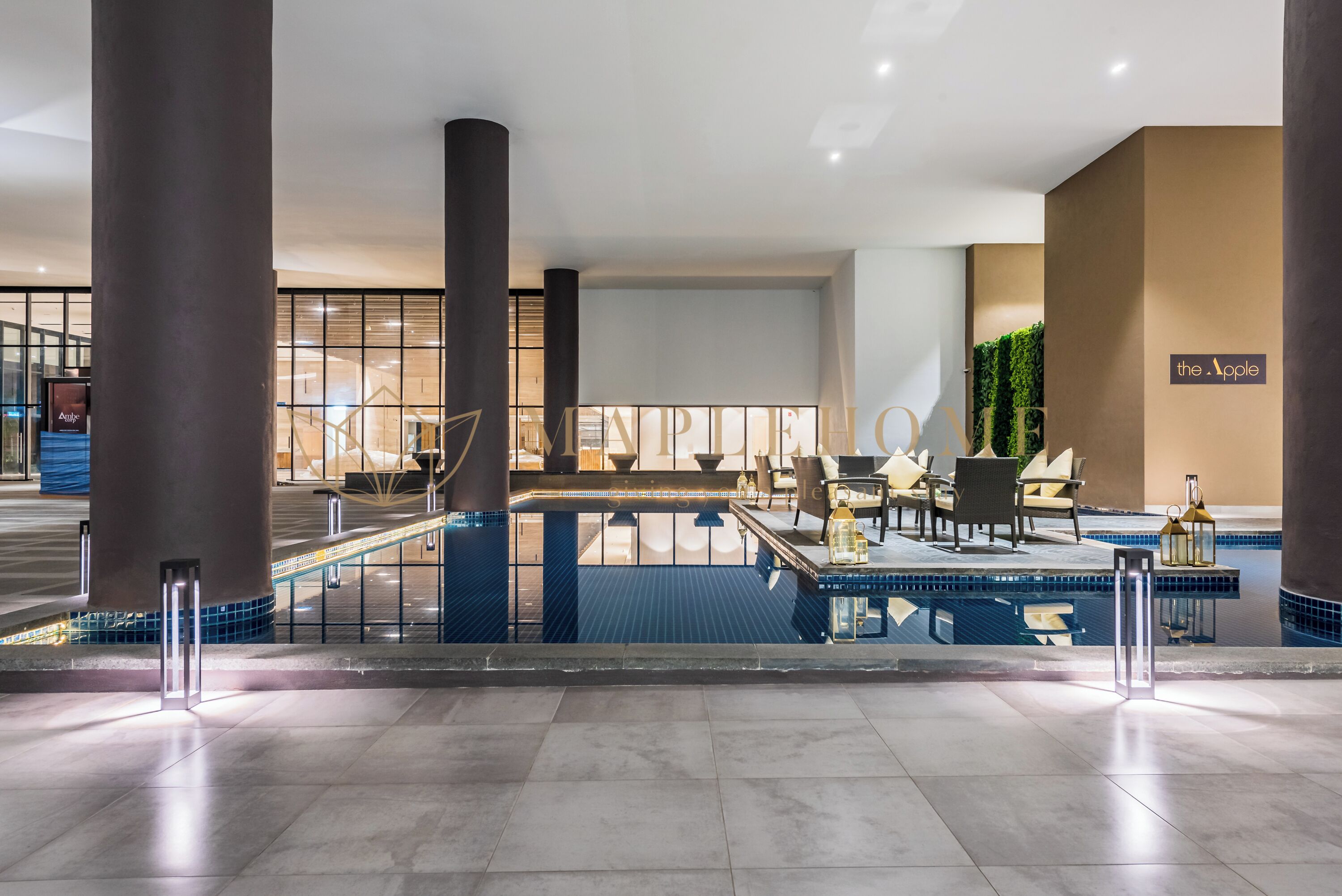 A modern indoor pool area with seating and a sign reading "the Apple".