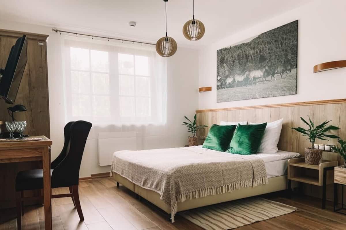 Ein Schlafzimmer mit Bett, Schreibtisch, Stuhl, Fenster und einem Bild an der Wand.