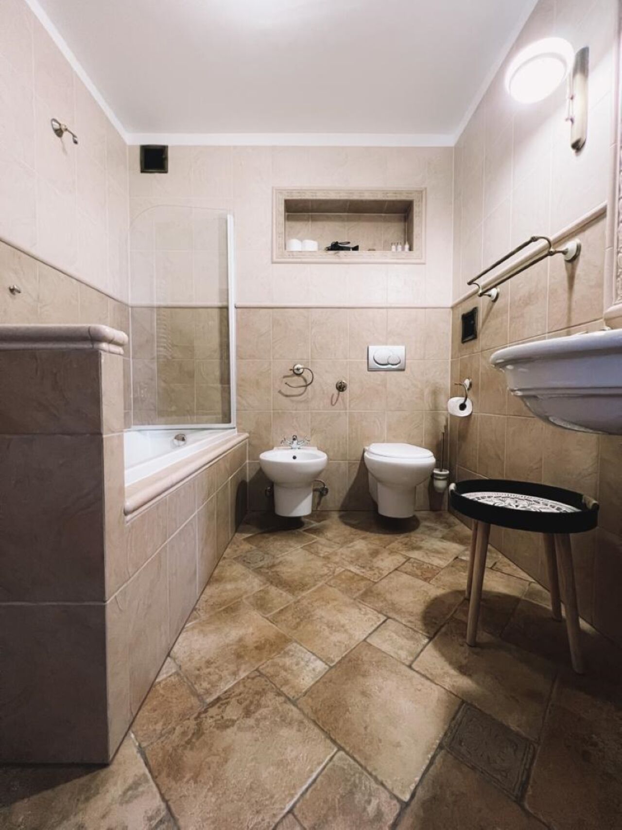 Ein kleines Badezimmer mit Badewanne, zwei Toiletten, Waschbecken und einem kleinen Spiegel.