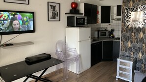 Eine kompakte Küche mit Mikrowelle, Kühlschrank und einer kleinen Essecke mit Tisch und Stühlen.