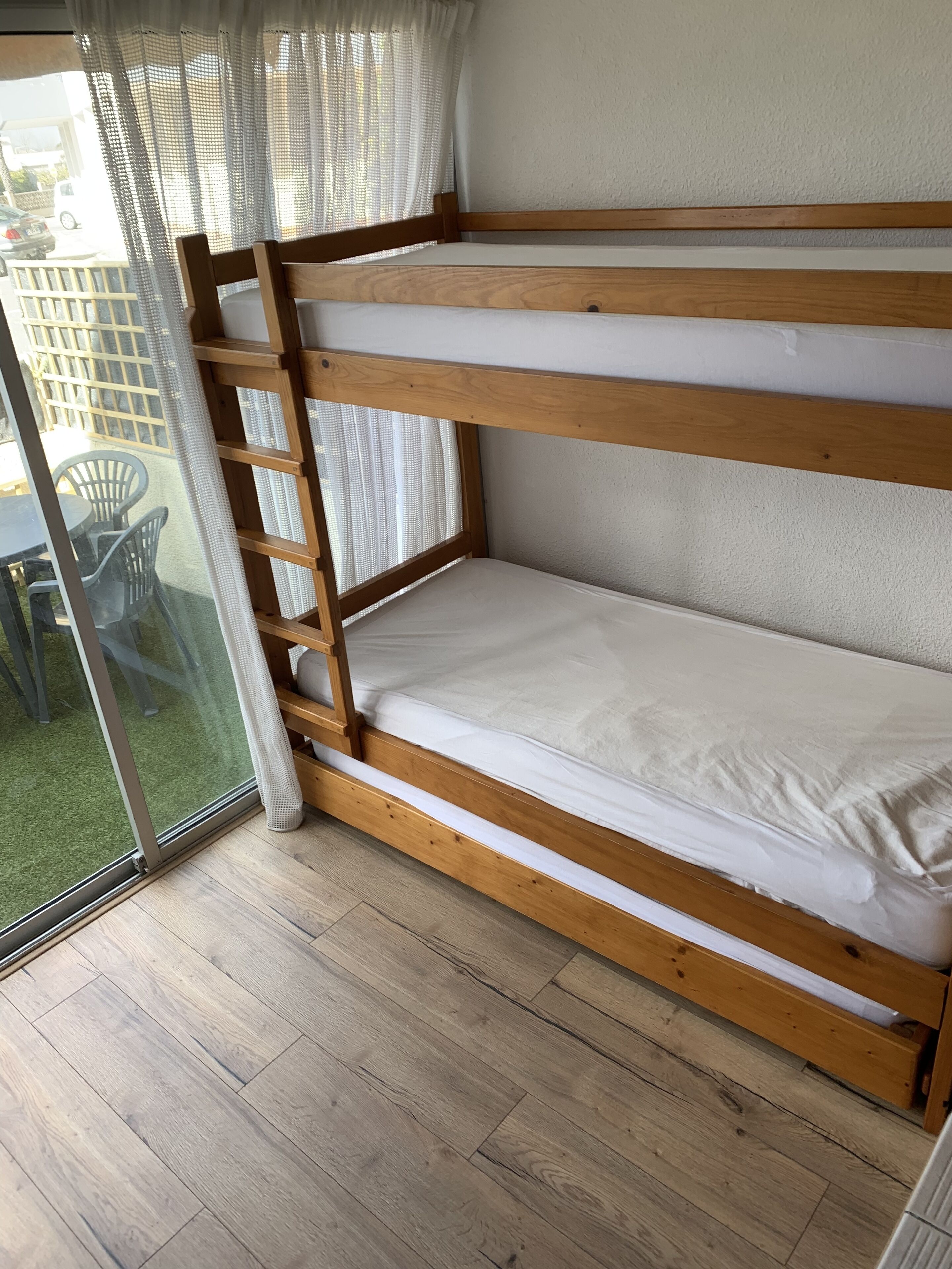 A bunk bed with a wooden frame and white bedding.