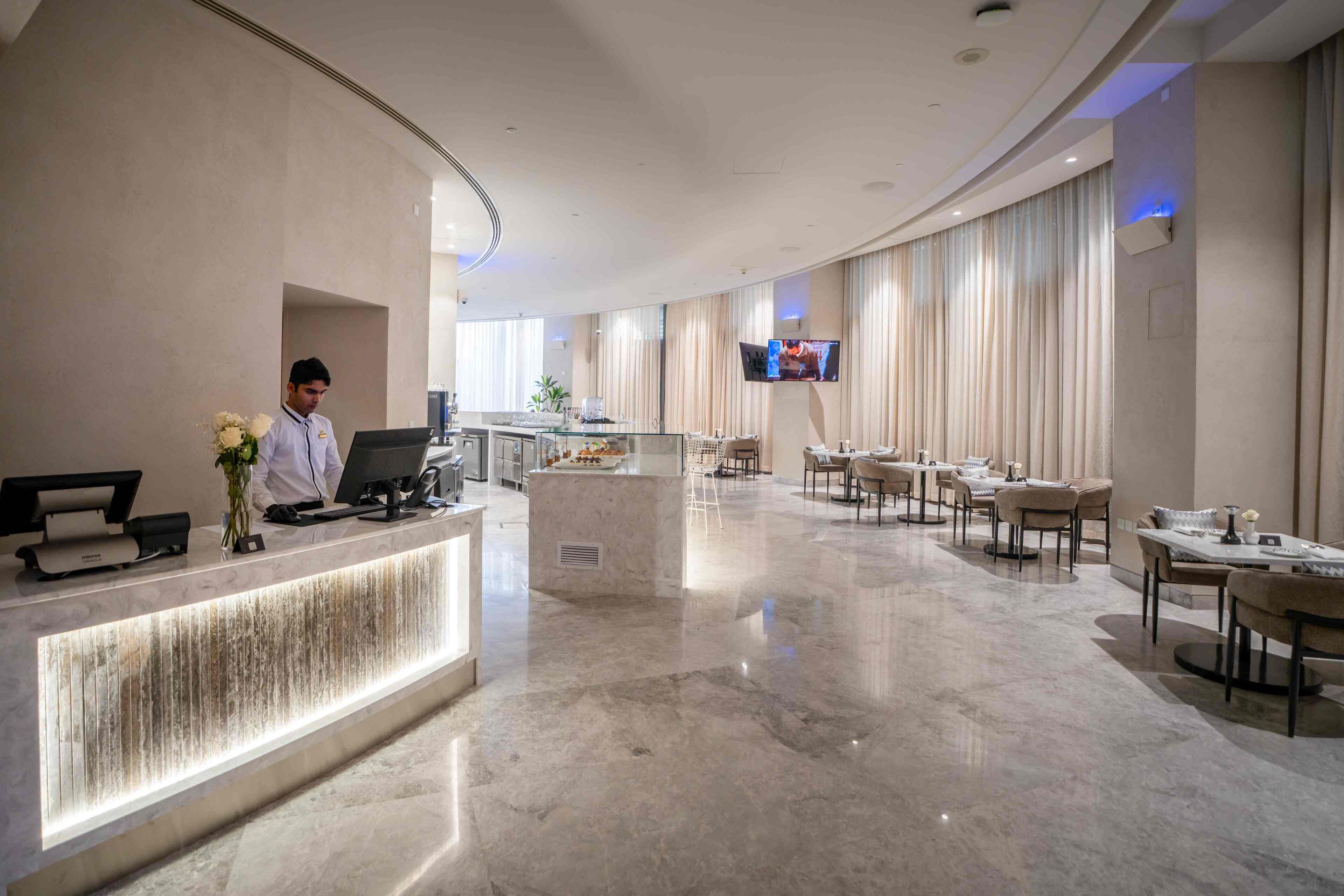 A hotel lobby with a reception desk, seating area, and a TV mounted on the wall.