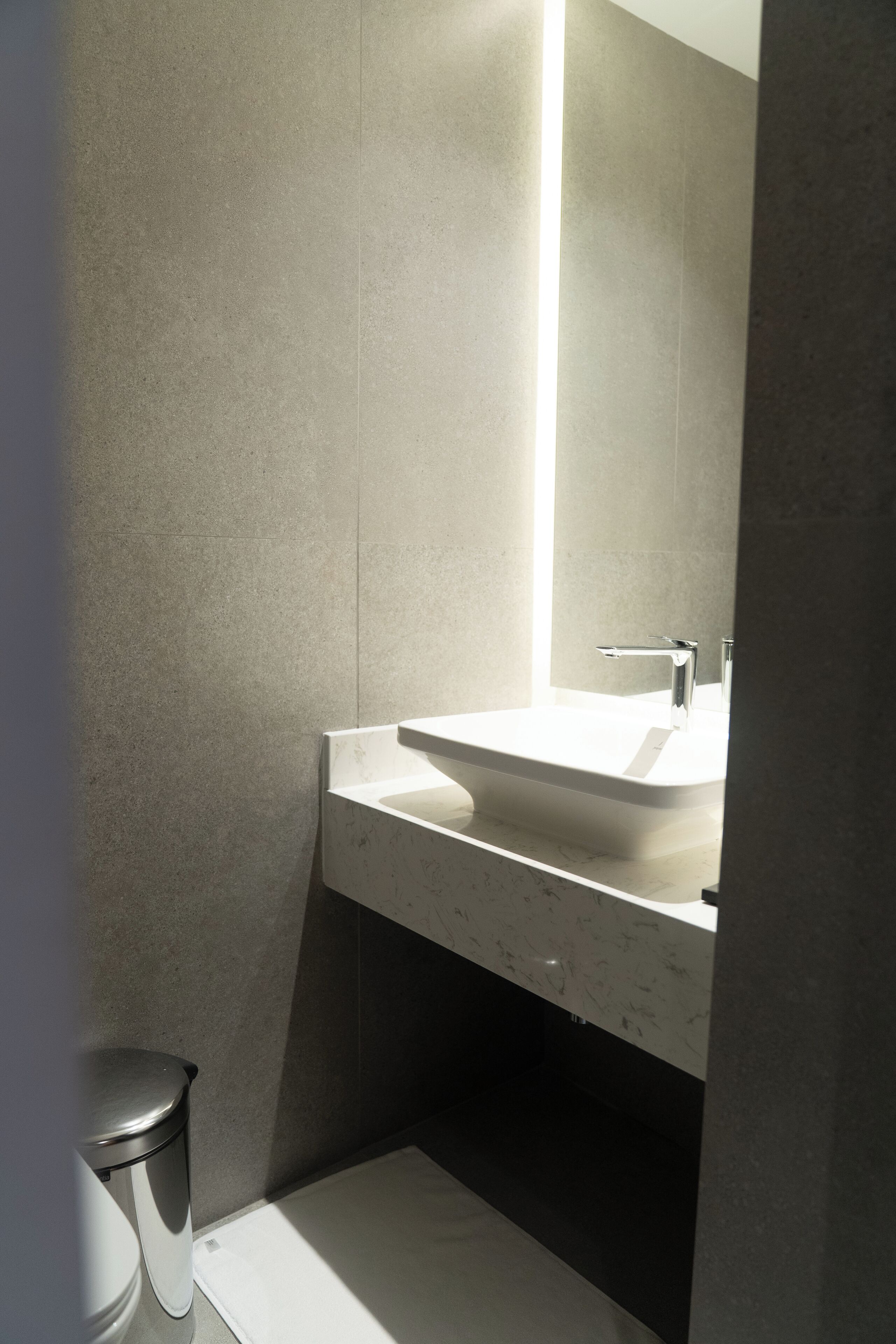 A modern bathroom with a white sink, a mirror, and a toilet.