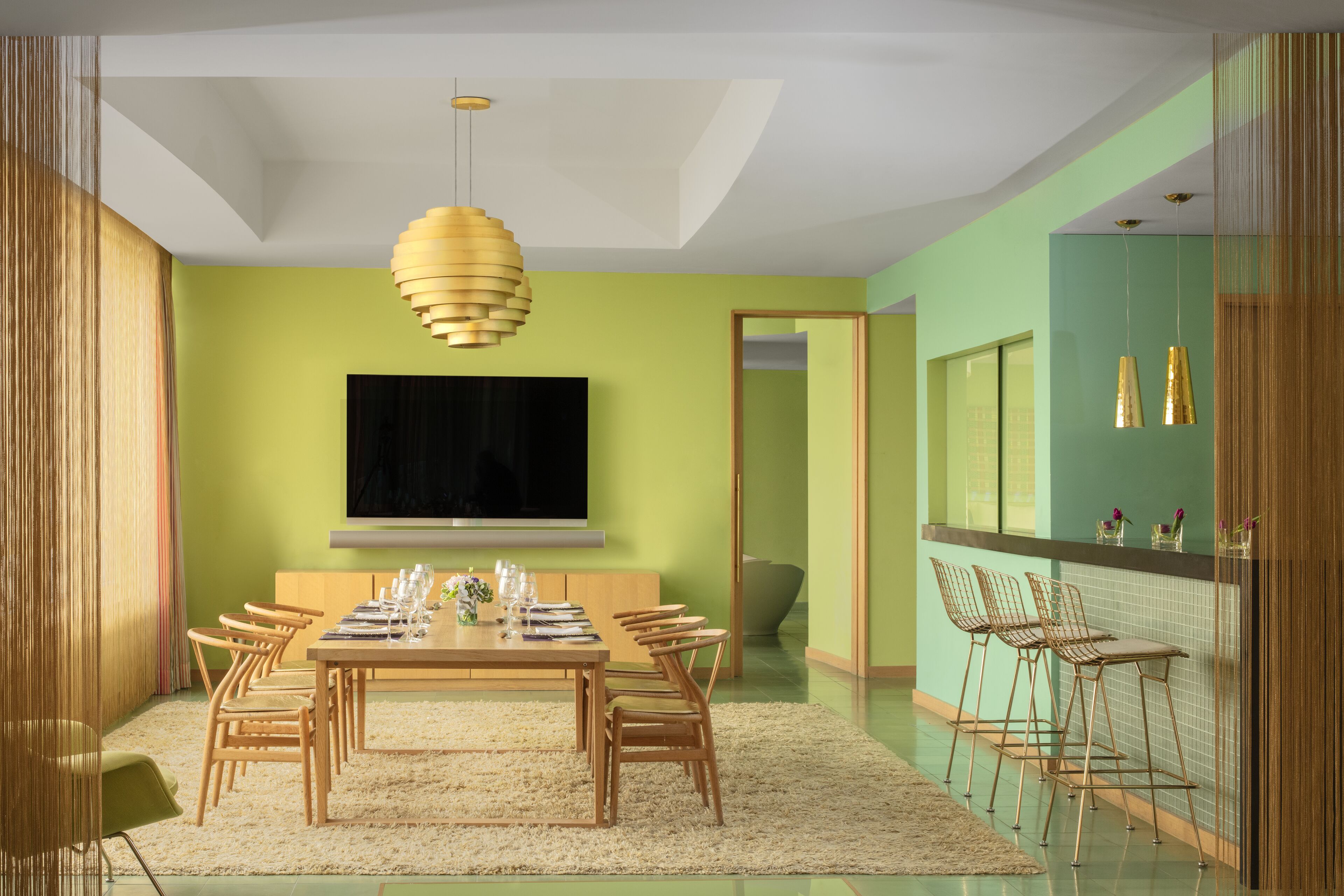 Un comedor moderno con una mesa grande, sillas y un televisor montado en la pared.