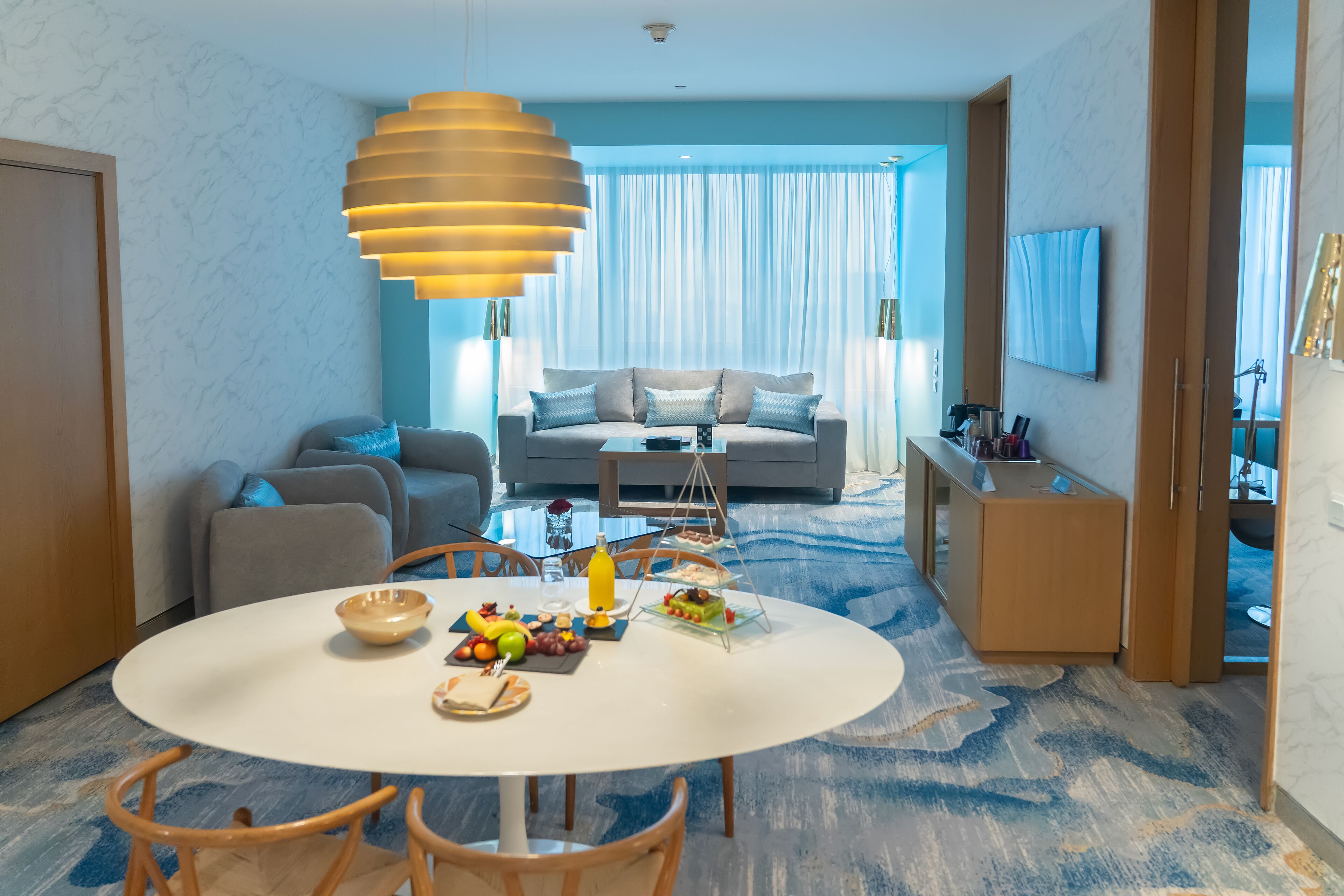 Une chambre d’hôtel moderne dotée d’un coin repas, d’un canapé et d’une télévision.
