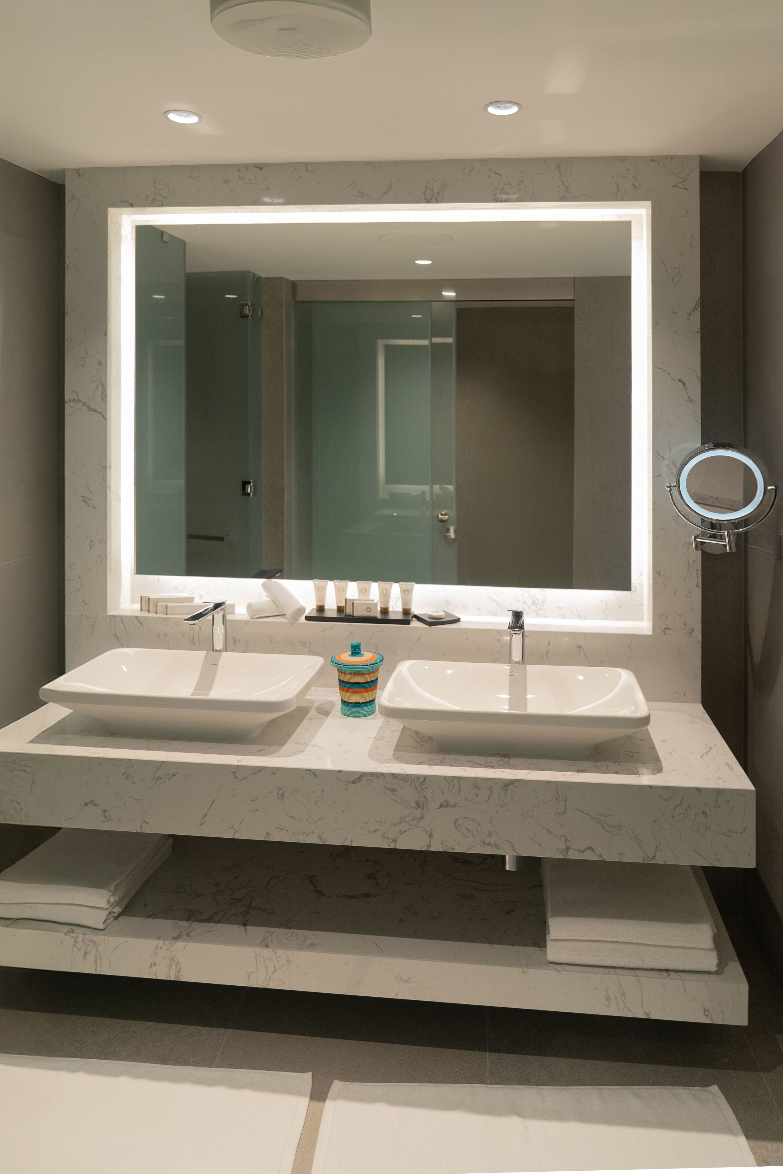 Ein modernes Badezimmer mit zwei Waschbecken, einem großen Spiegel und einem Waschtisch mit Marmorplatte.