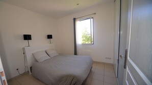 A bedroom with a bed, two bedside lamps, a window, and a door.