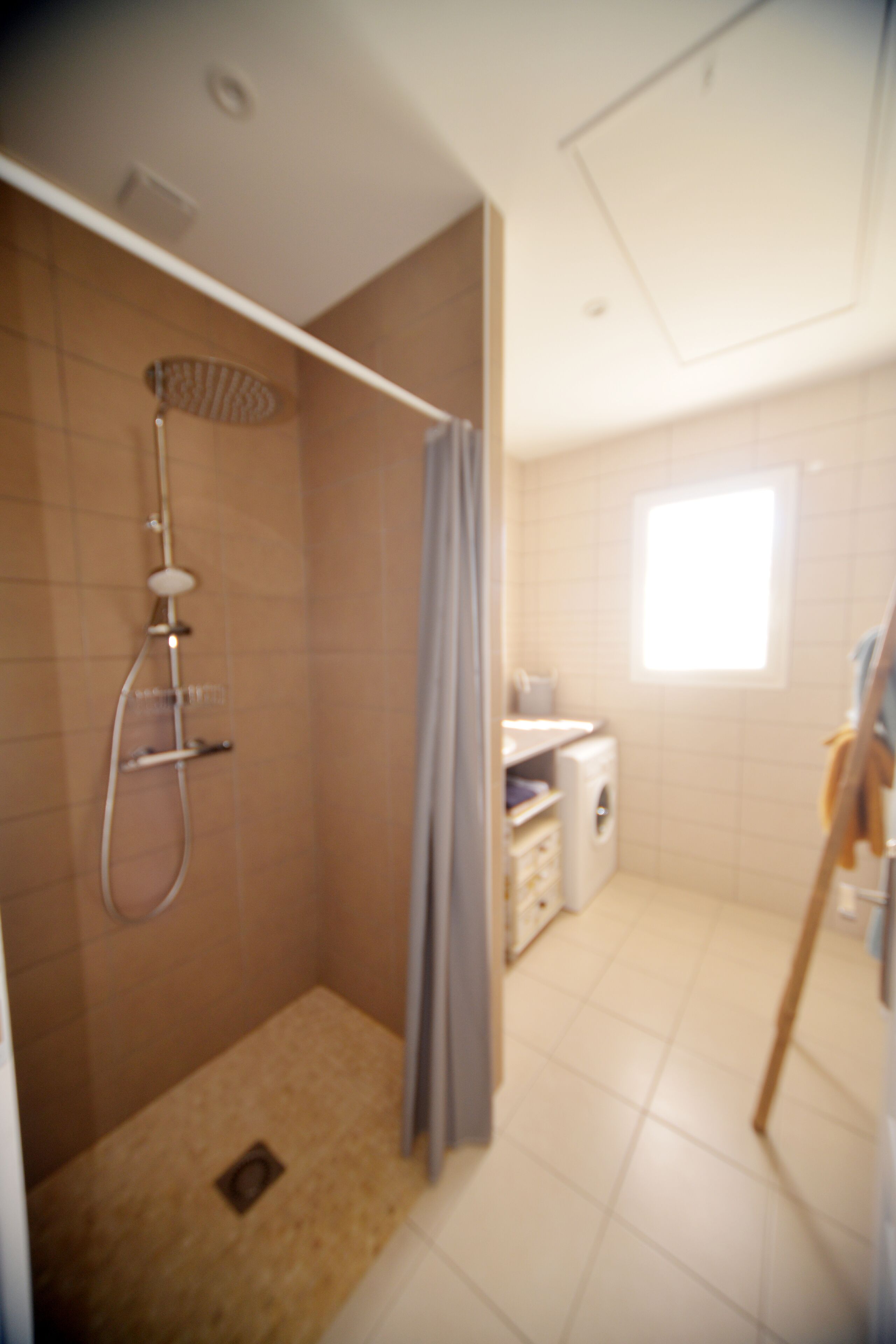 A small, tiled bathroom with a shower, a toilet, and a sink.
