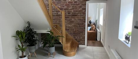 Een modern interieur met een houten trap, bakstenen muur en potplanten.