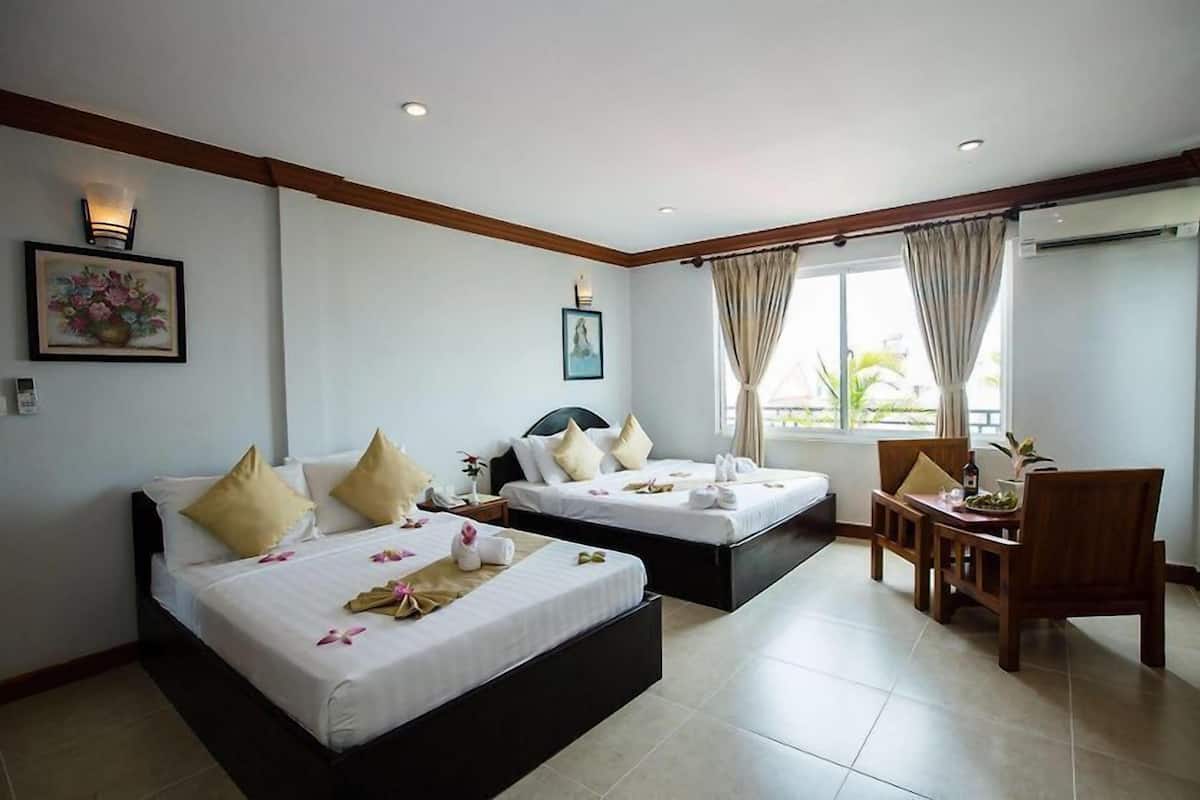 A hotel room with two beds, a dining area, and a large window with curtains.