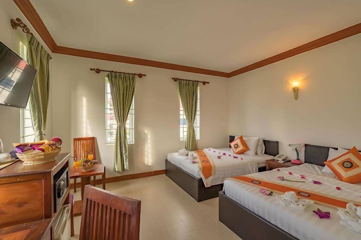 A hotel room with a bed, a desk, a chair, and a television.