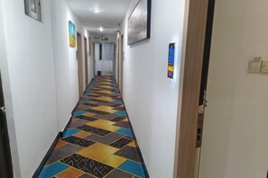 A hotel hallway with patterned carpet, doors on either side, and framed pictures on the walls. - Zhang Ying Hotel (Dongguan)