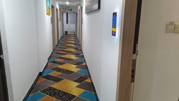 Un couloir doté d’un sol à motifs, de murs blancs et de portes donnant sur différentes pièces.