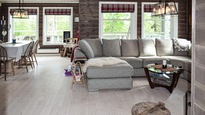 A cozy living room with a grey sectional sofa, a small round table, and a wooden barrel. - 4 bedroom pet friendly home in Eggedal (Eggedal)