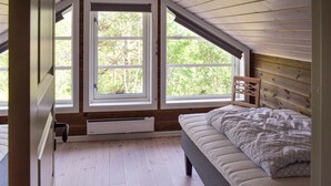 A bedroom with a sloped ceiling, a bed with a patterned blanket, and a window with a view of trees. - 4 bedroom pet friendly home in Eggedal (Eggedal)