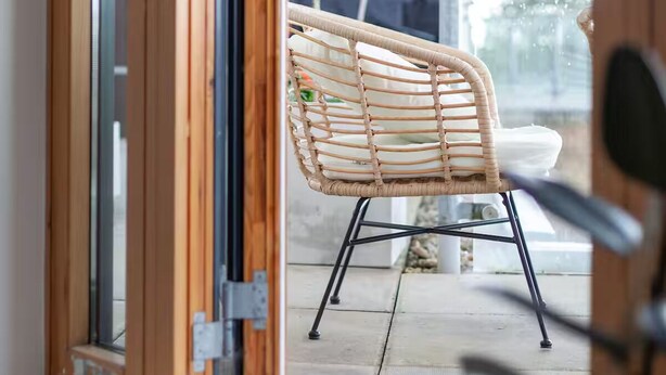 A wicker chair outside a building with a view of a tree and a car in the background. - Luxury Penthouse Near Notting Hill Gate | Stunning Sunset Views (London)