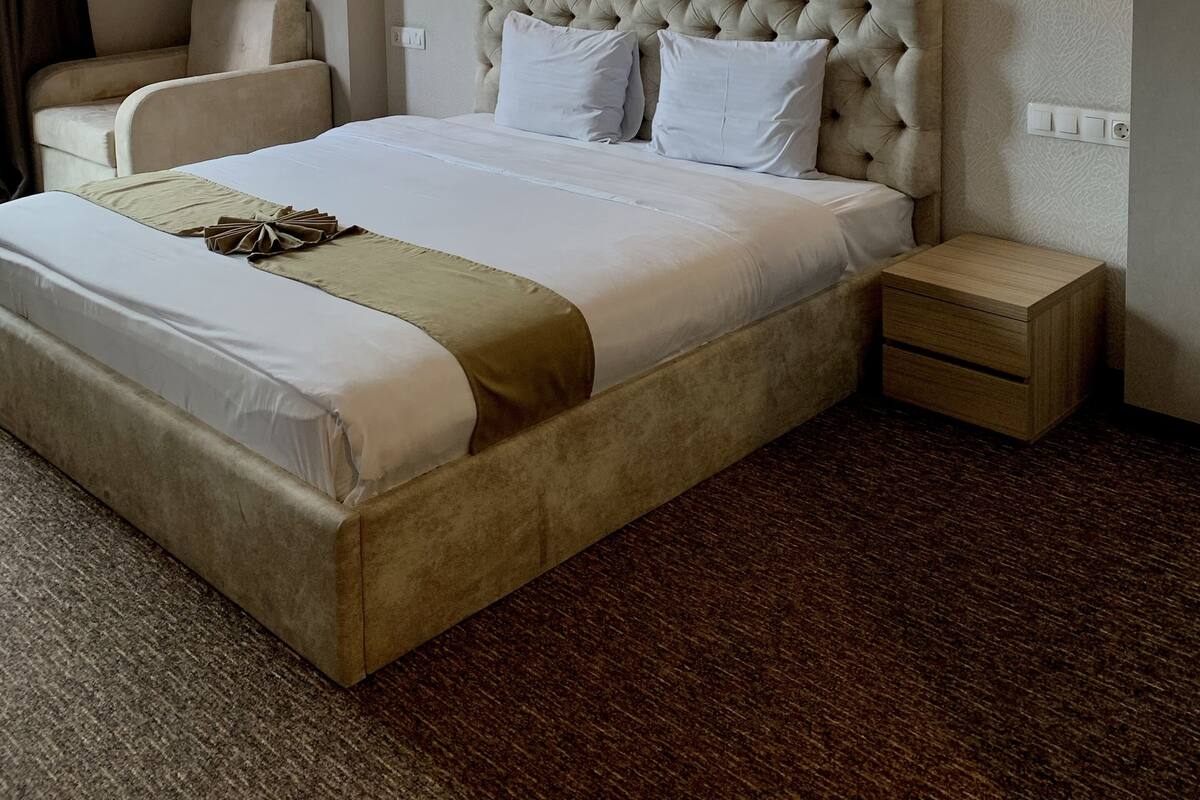 A hotel room with a large bed, two bedside tables, a chair, and two wall-mounted lights.