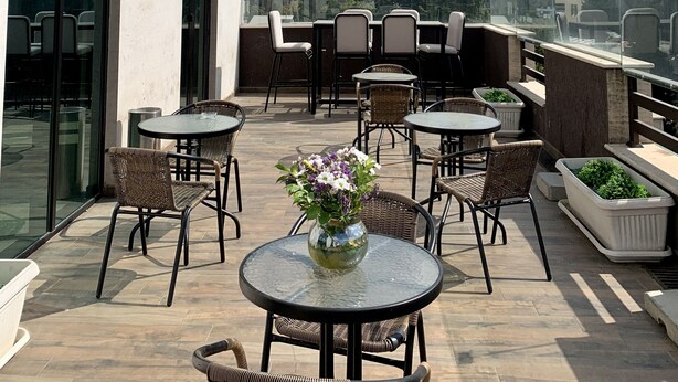 A rooftop terrace with outdoor seating, a glass balustrade, and a view of the cityscape. - Betlem Hotel (Tbilisi)