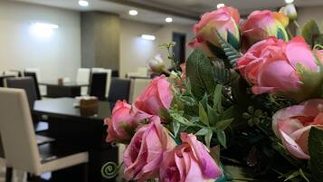 A conference room with a table and chairs, a floral arrangement on a table, and ceiling lights.