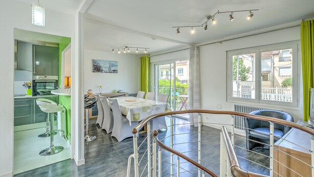 Una cocina moderna con horno empotrado y comedor con mesa y sillas.