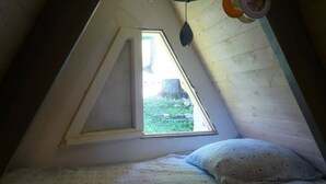 A small, triangular attic bedroom with a single window, a bed, and a hanging light fixture. - Chalet Guzet Snow (Seix)