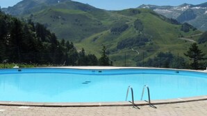 A swimming pool with a mountain view, surrounded by greenery and a paved walkway. - Chalet Guzet Snow (Seix)