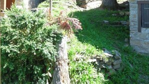 A rustic cabin with stone walls, surrounded by lush greenery and trees. - Chalet Guzet Snow (Seix)