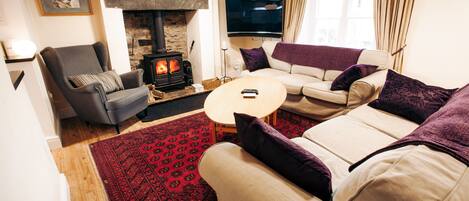 A cozy living room with a fireplace, a sofa, a chair, and a television.
