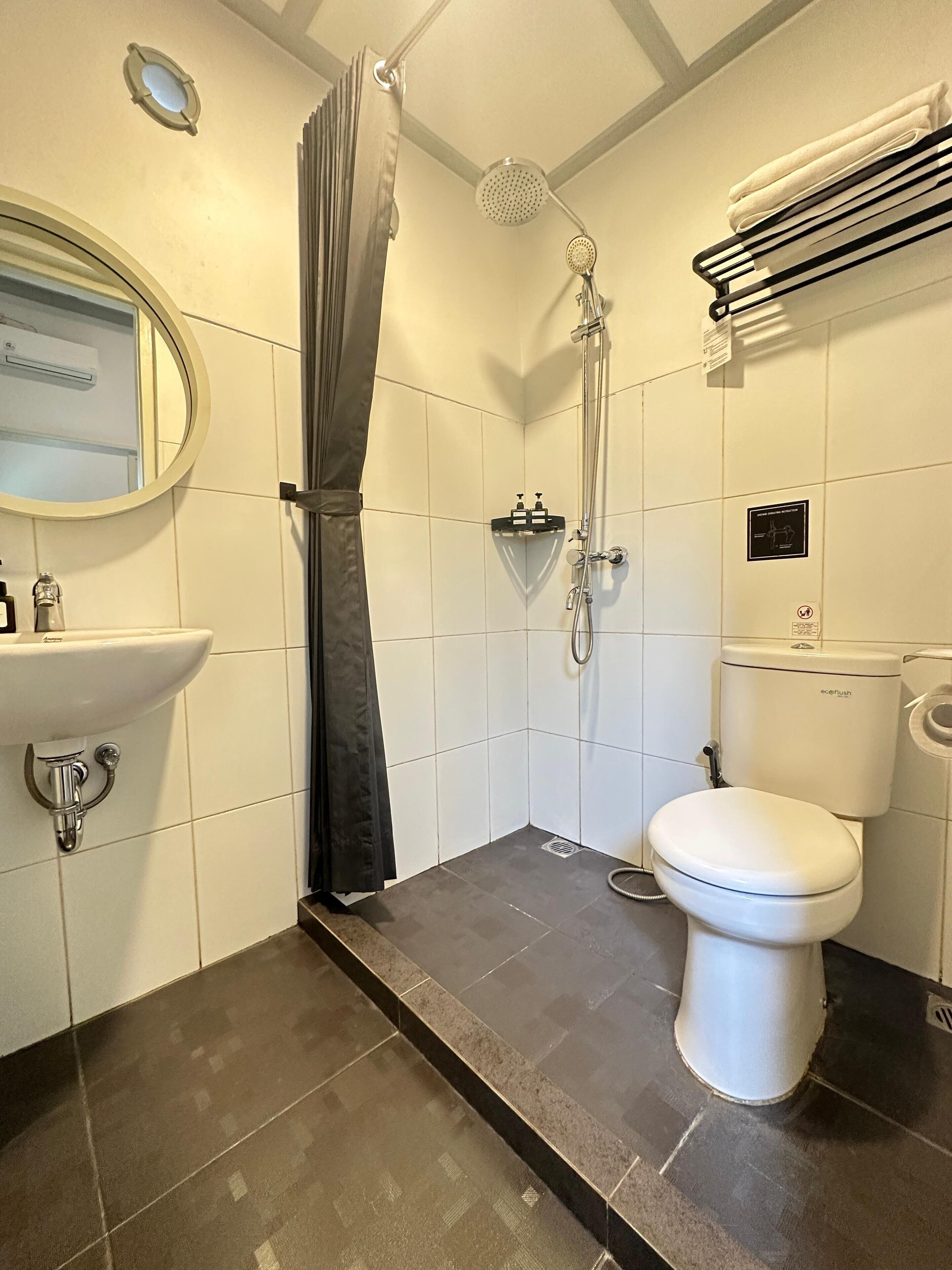 A bathroom with a shower, toilet, sink, and a towel rack.