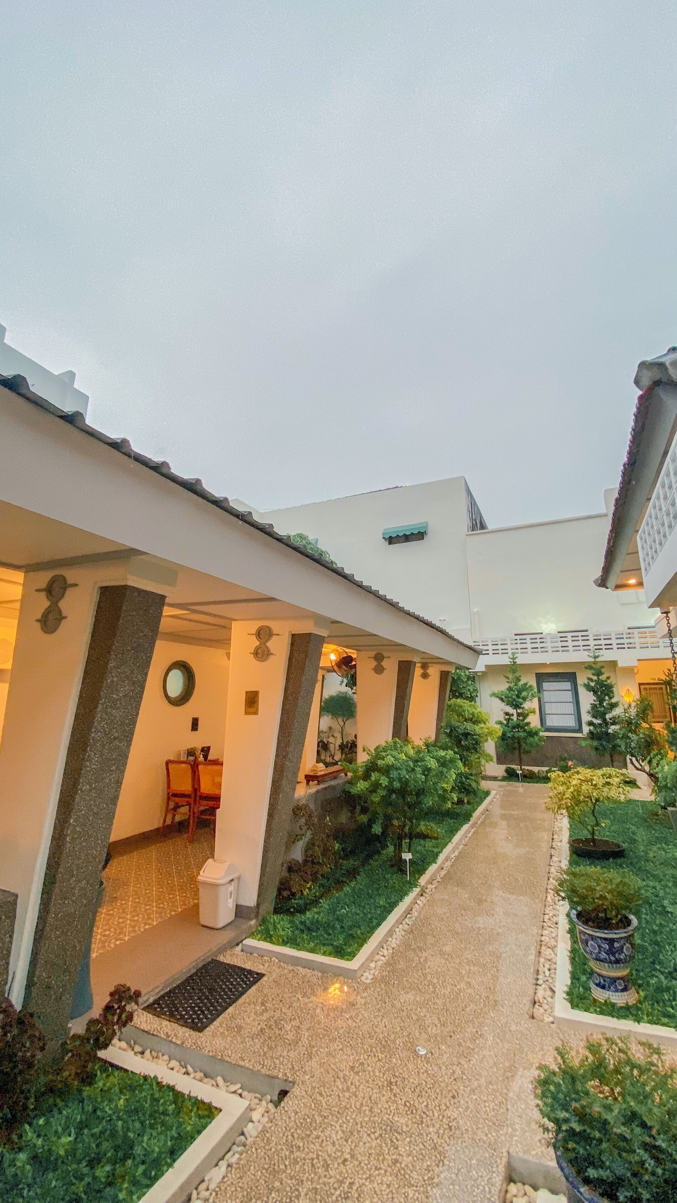 A courtyard with a covered walkway, a dining area, and a small garden with potted plants.