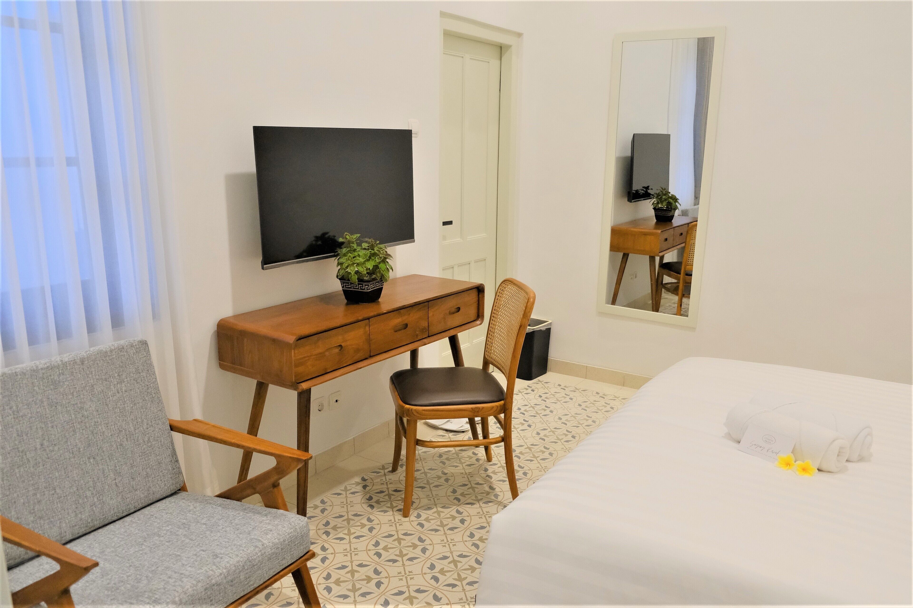 Une chambre d’hôtel comprenant un lit, un bureau avec une chaise, une télévision et un miroir.