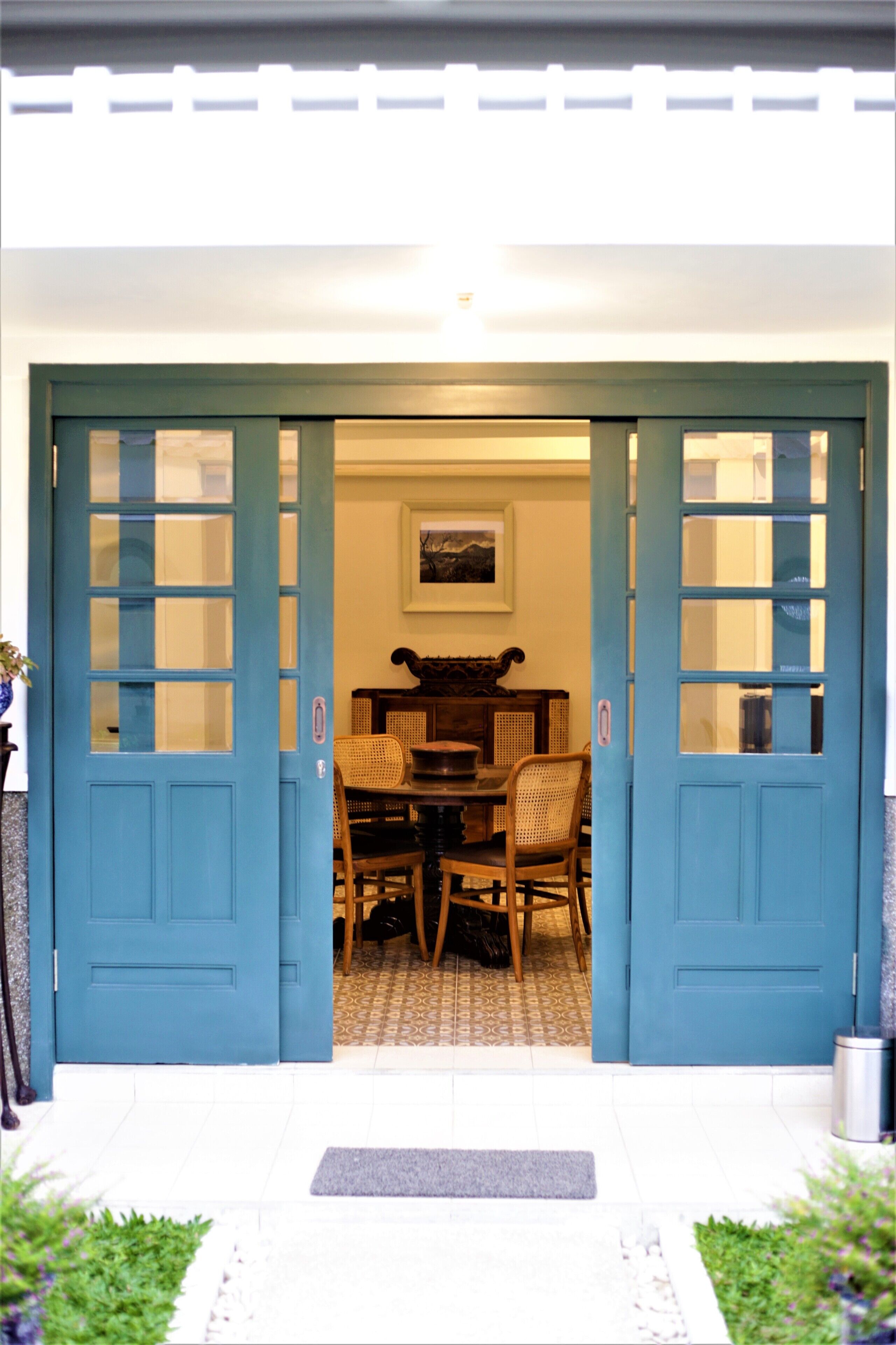 A blue door with glass panels leading to a room with a table and chairs.