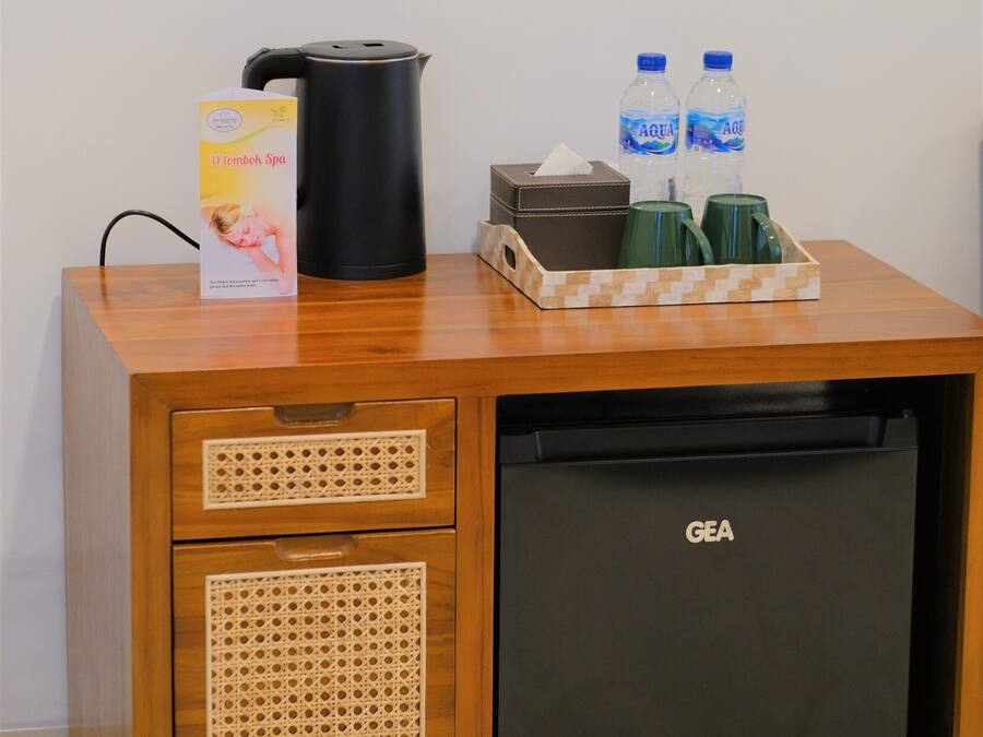 A compact minibar with a GEA refrigerator, a black coffee maker, two water bottles, and a tissue box.