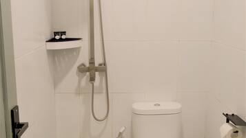A small bathroom with a toilet, a sink, and a shower.