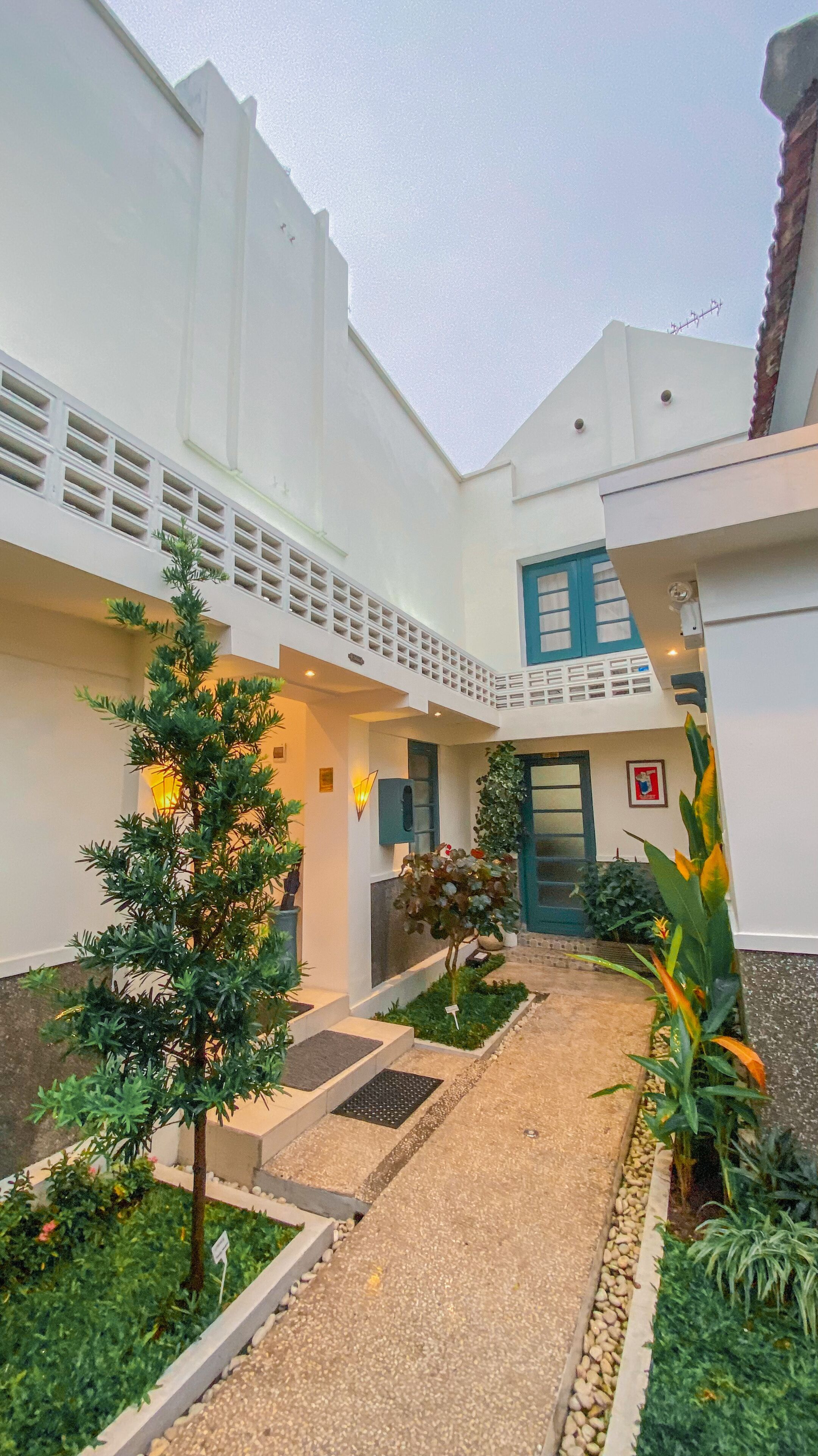 A modern building with a central courtyard, a staircase, and a variety of plants.