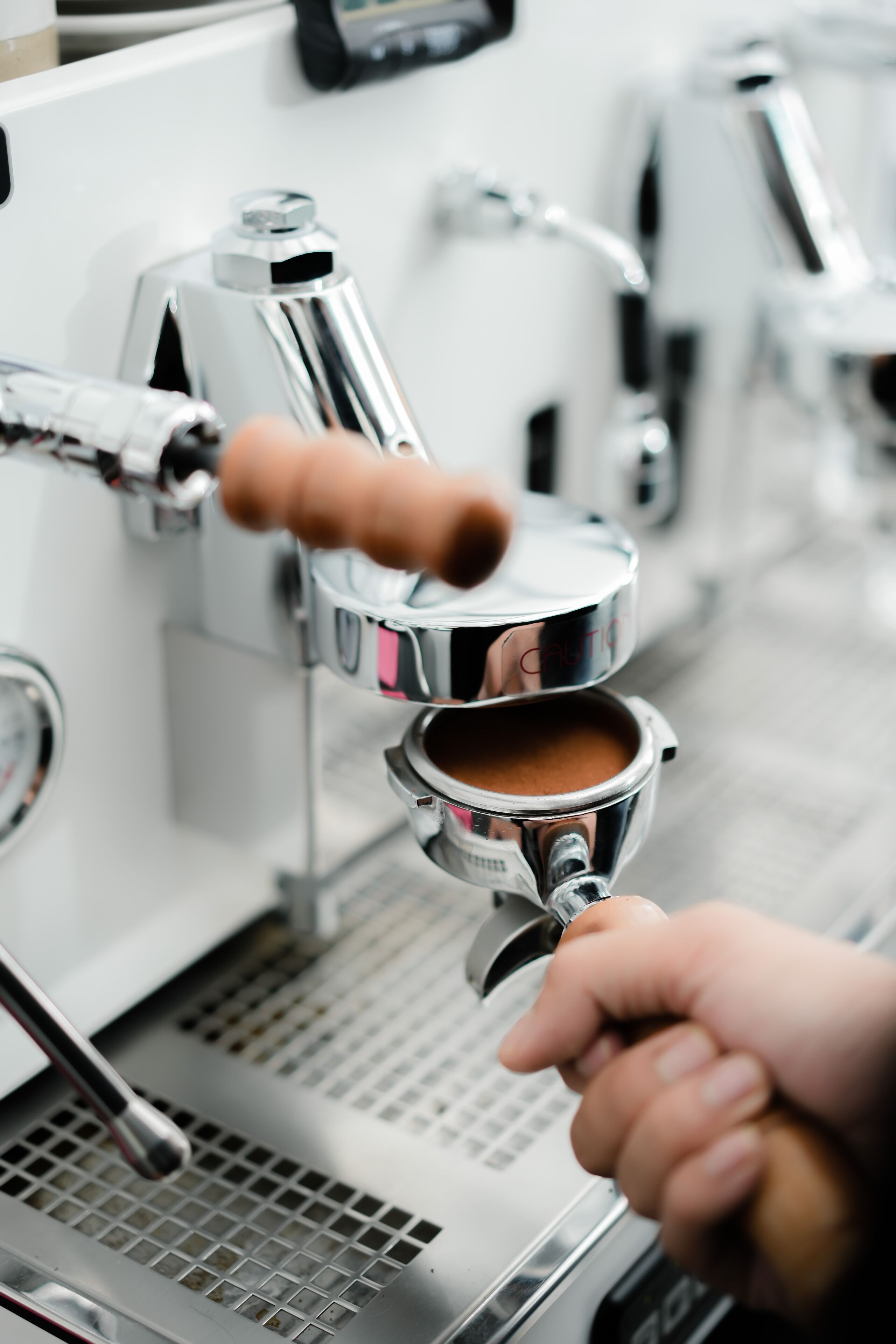 Gros plan d’une machine à café, avec une main tenant le porte-filtre.