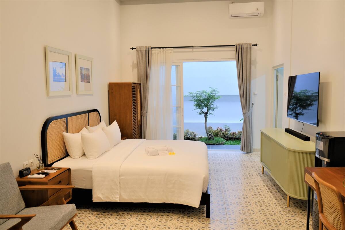 Een hotelkamer met een bed, een televisie, een bureau en uitzicht op zee.
