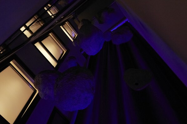 A room with a large window, a hanging light fixture, and a curtain. - Athens Woo Suites (Athens)