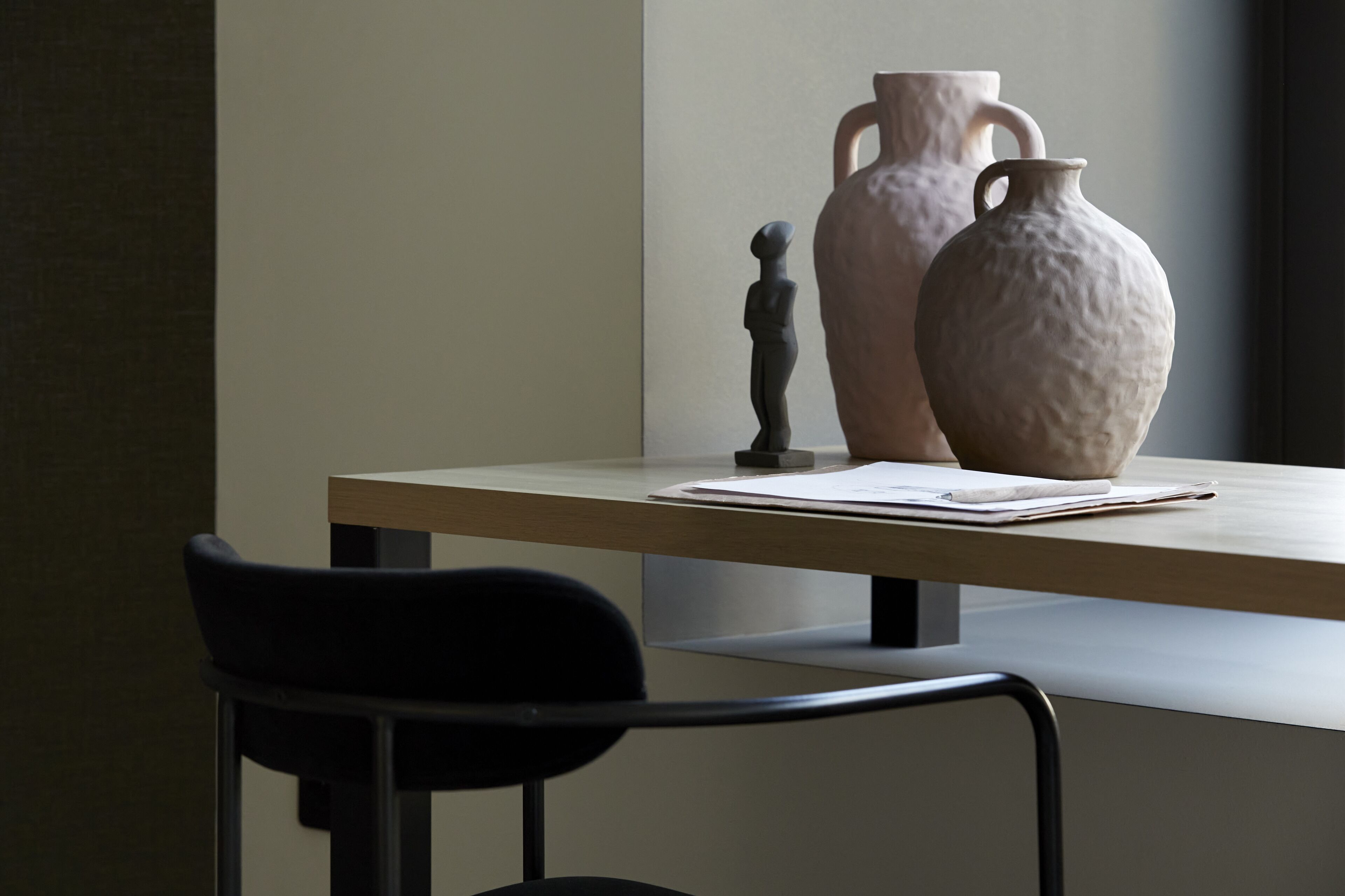 Una mesa con dos jarrones de cerámica y una figurita.
