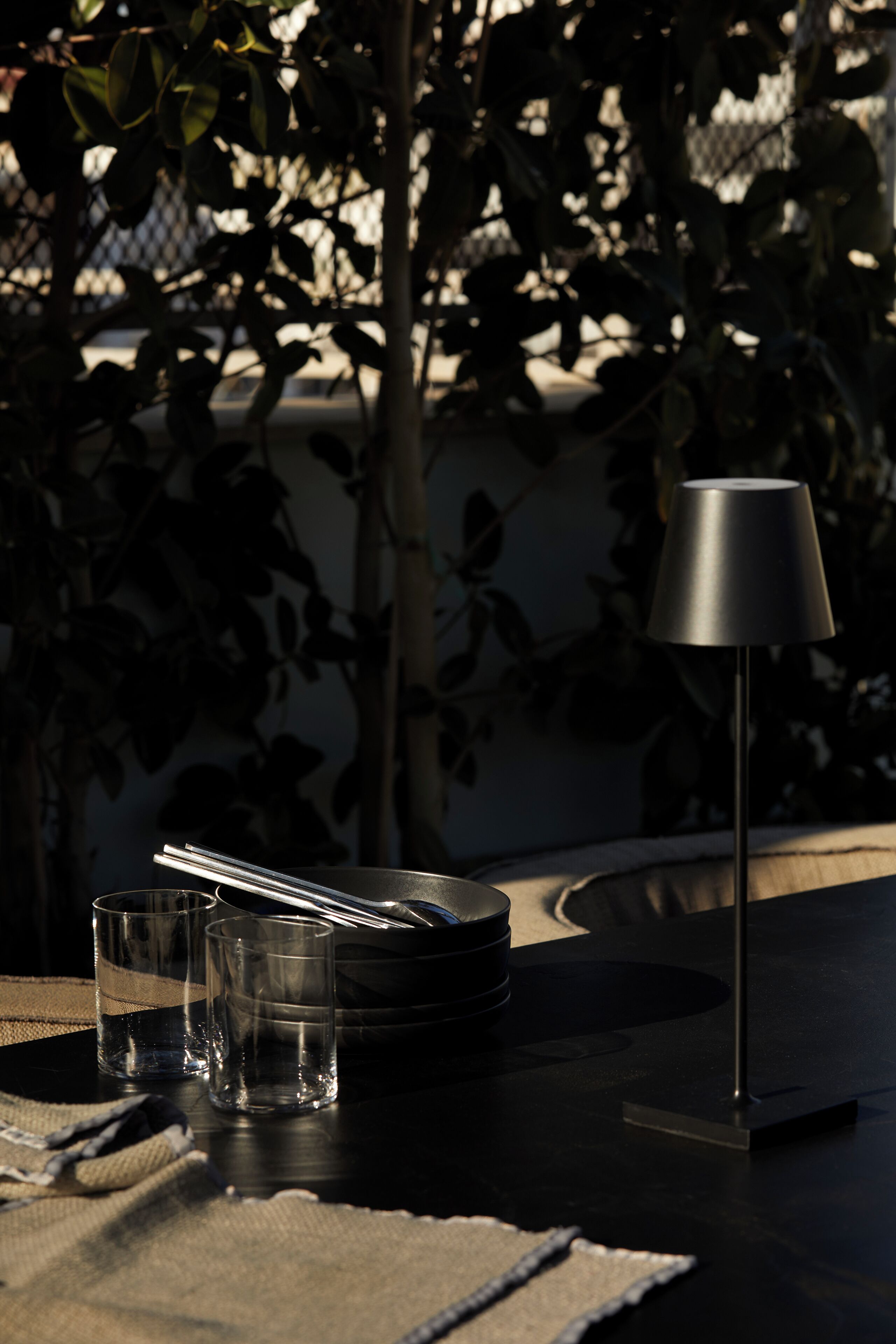 A table with a lamp, glasses, and a guitar.