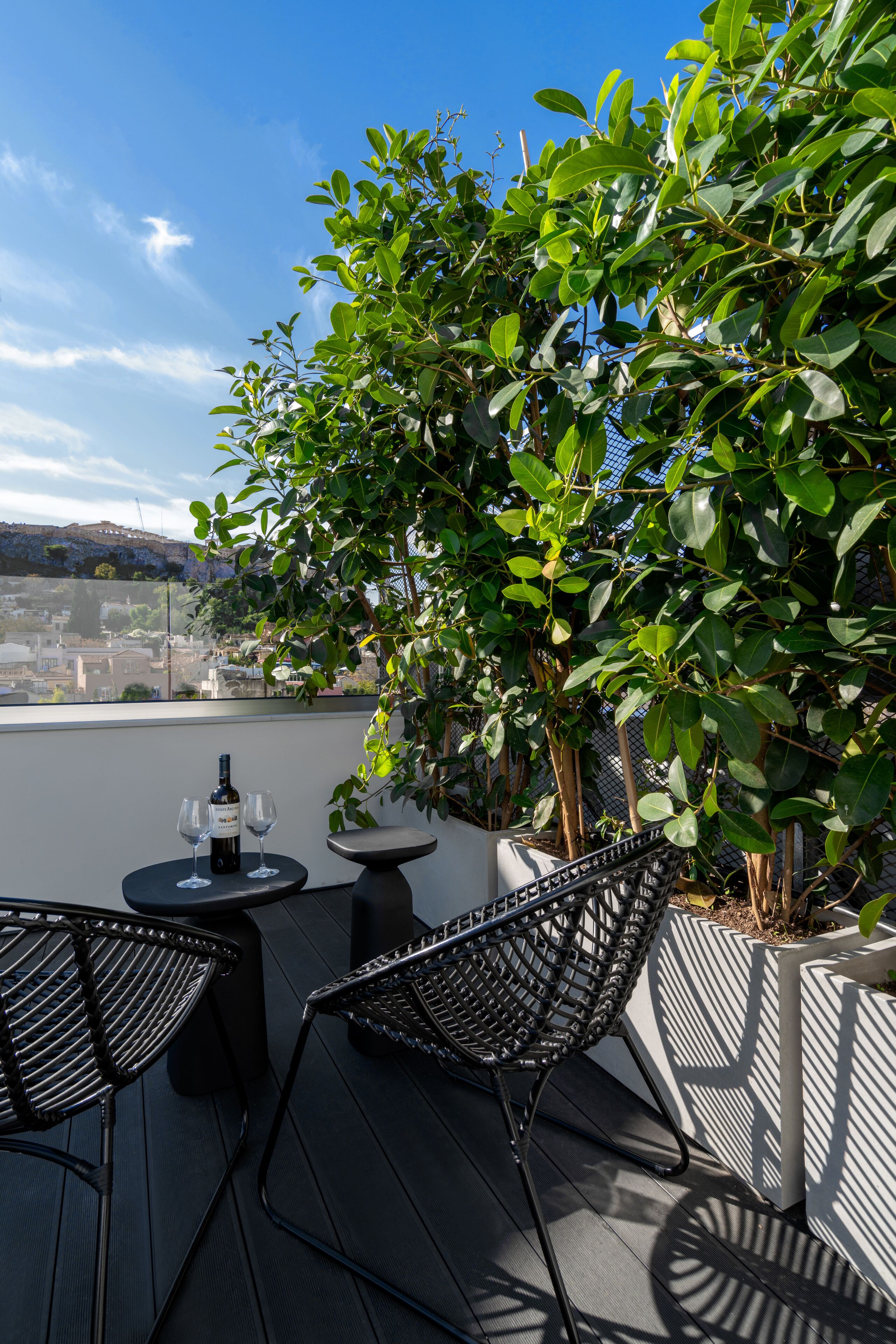 Une terrasse sur le toit avec deux tables, deux chaises, une bouteille de vin et une vue sur le paysage urbain.