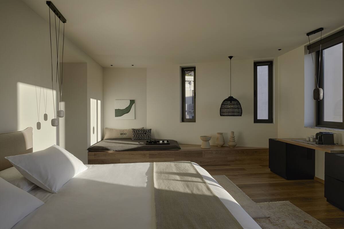 A modern bedroom with a large bed, a desk, and a view of the city.