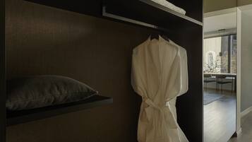 A modern interior with a dark wood shelving unit, a white robe hanging, and a view of a dining area through a glass door.