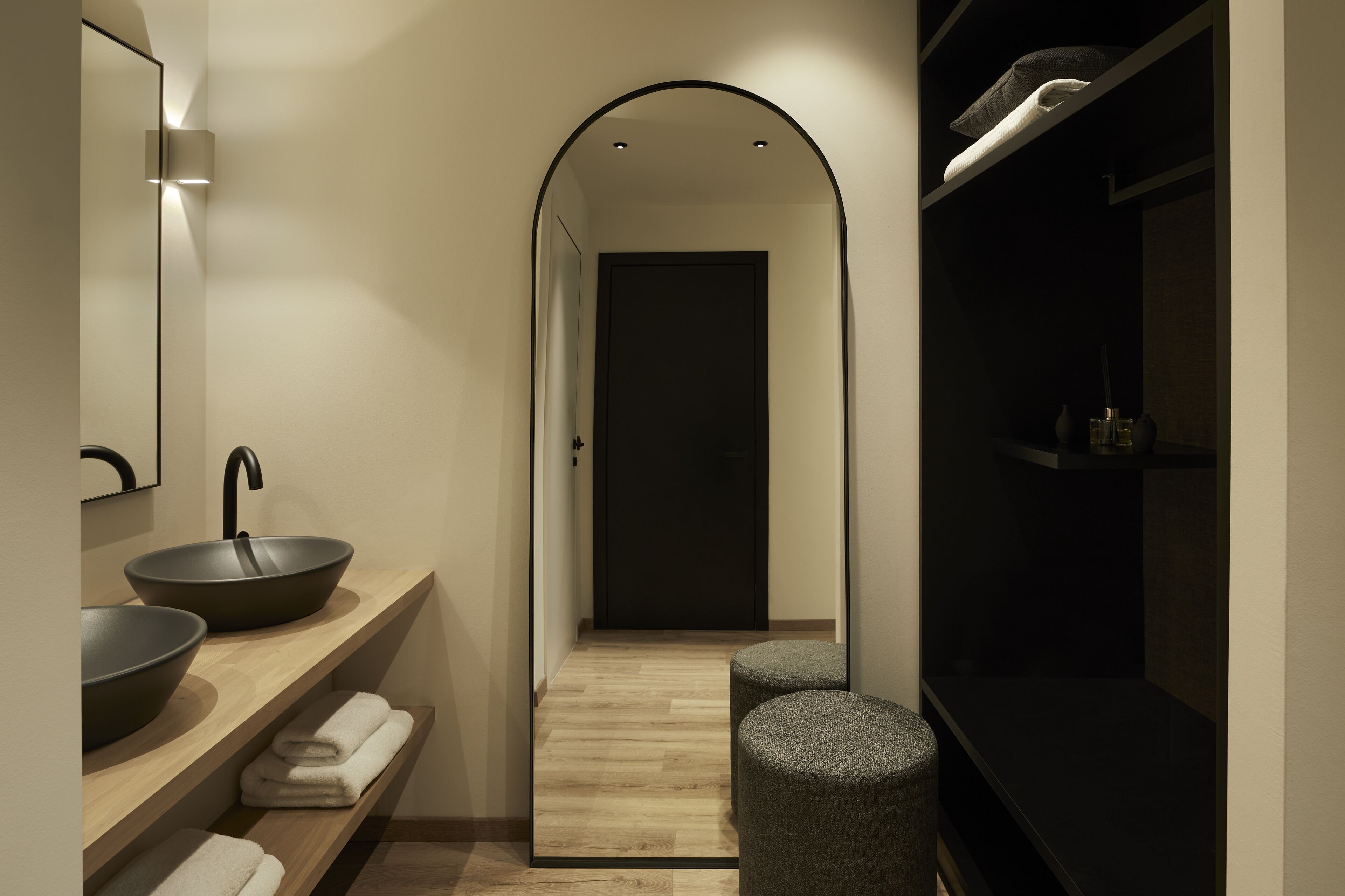 A modern bathroom with a large mirror, two sinks, a towel rack, and a dark vanity.